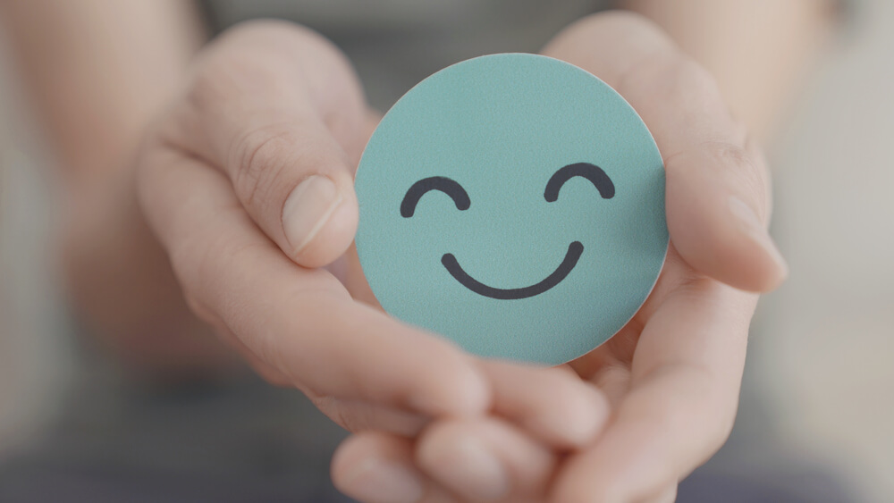 Hands holding green happy smile face