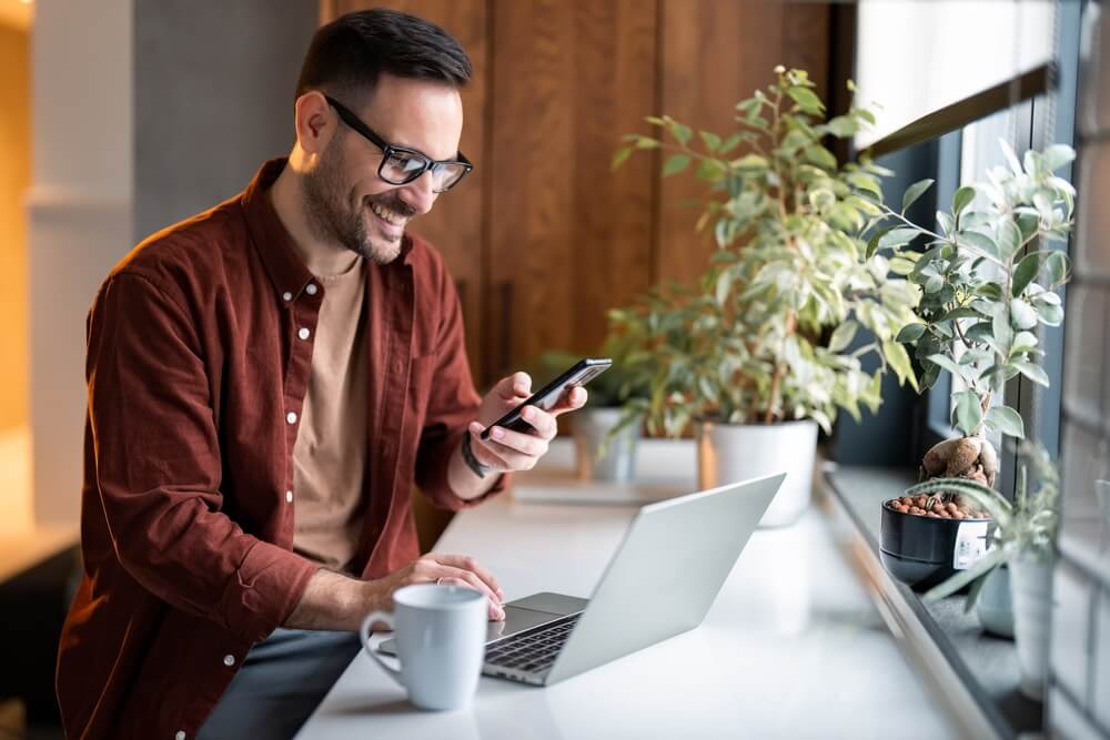 Satisfied modern man in stylish casual clothes using smartphone